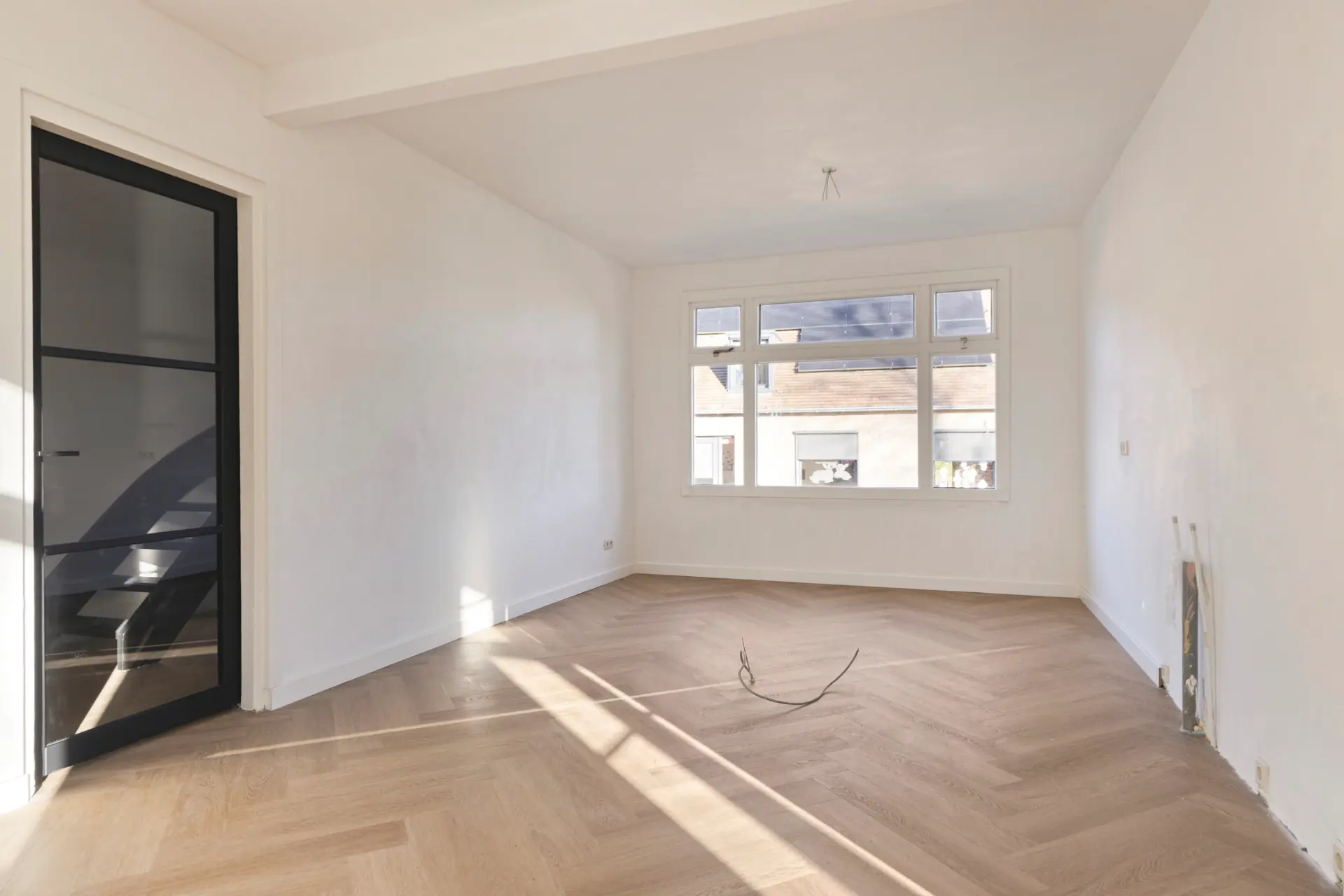Lichte woonkamer met visgraat parket en strak wit stucwerk
